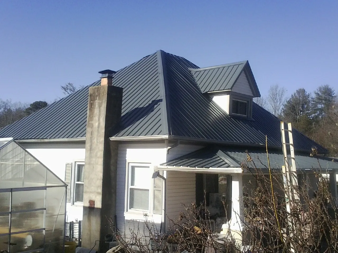 Dark blue standing seam metal roof on a white farmhouse with dormer — Slate & Tile Roof Repair by Roofing Brothers in Roseburg