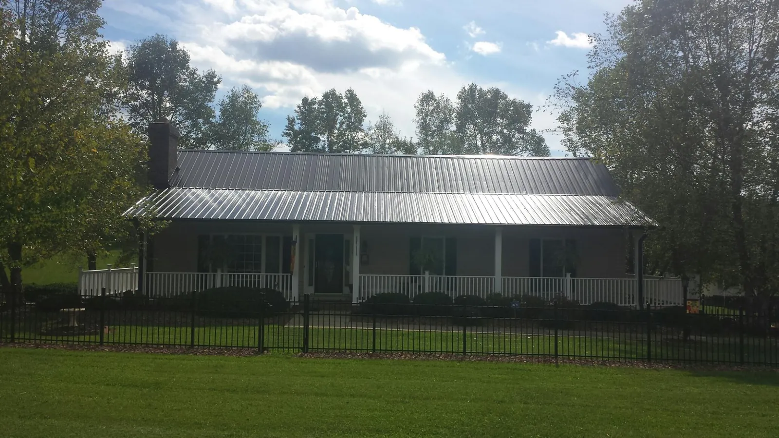 Gray metal roof on a brick ranch with a full width front porch — Gutter Guard Installation work by our crew in Roseburg