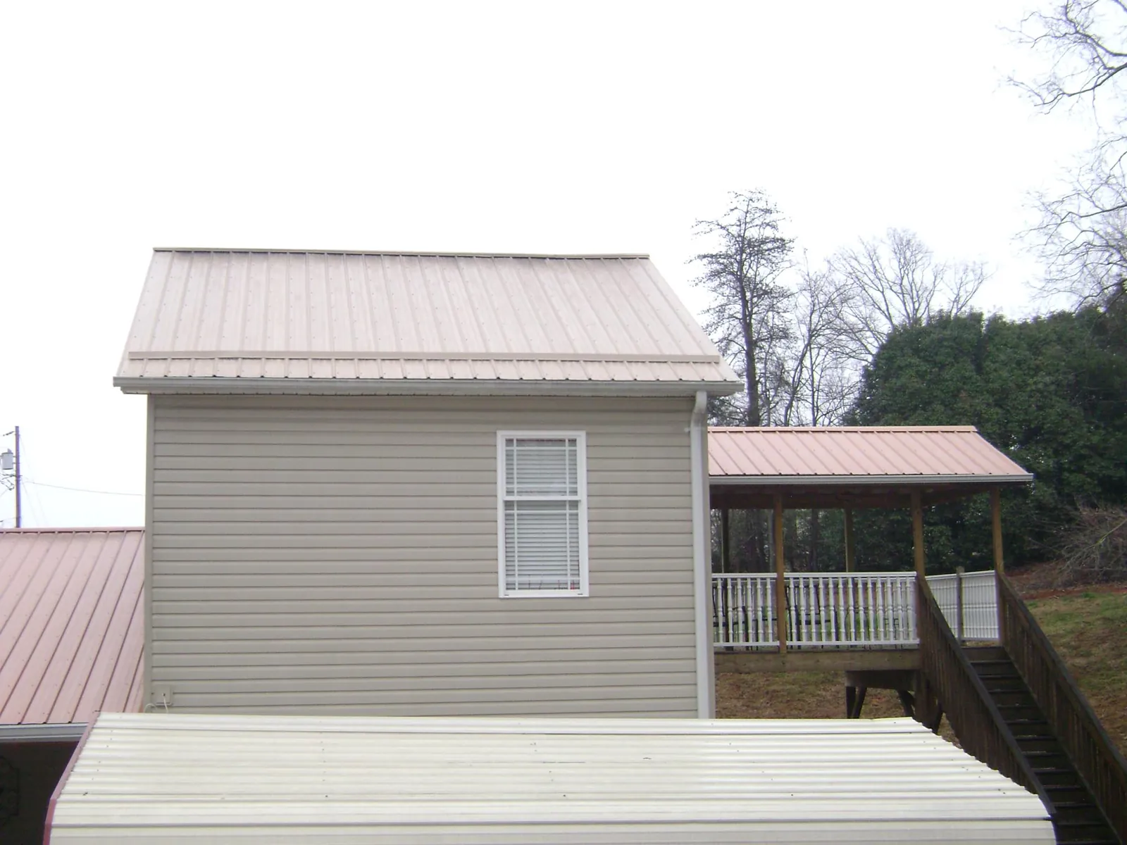 Tan metal roofs on a two story addition and attached porch, from a Roof Replacement job in Roseburg