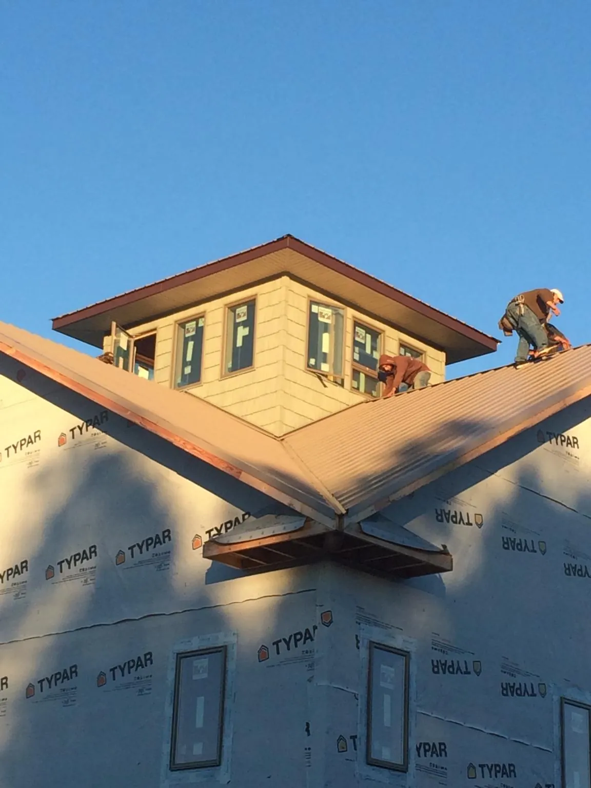 Roofers working around a rooftop cupola on a new metal roof at sunset — Roof Waterproofing in Roseburg by Roofing Brothers